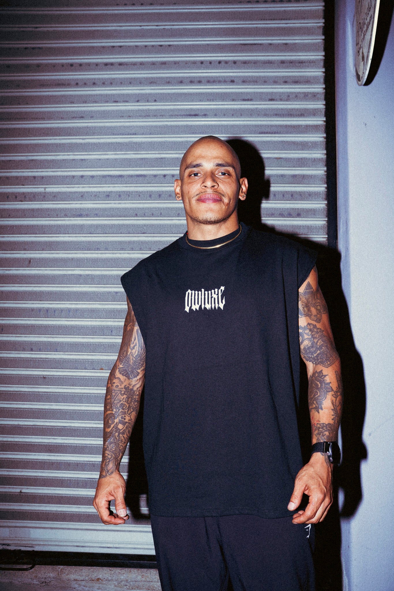Camiseta sin mangas oversize negra para hombre, vista frontal con logo OWLUXE