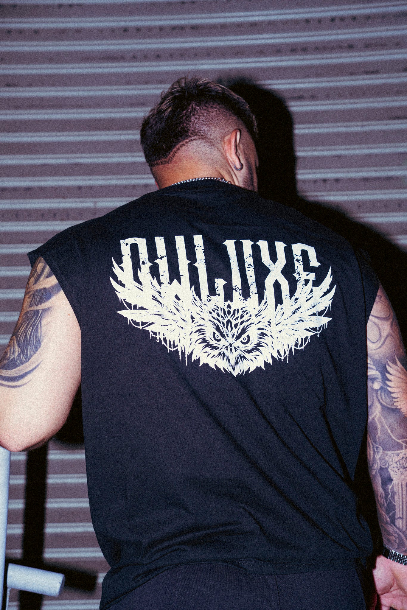 Detalle del estampado de búho y wordmark OWLUXE en la espalda de la camiseta