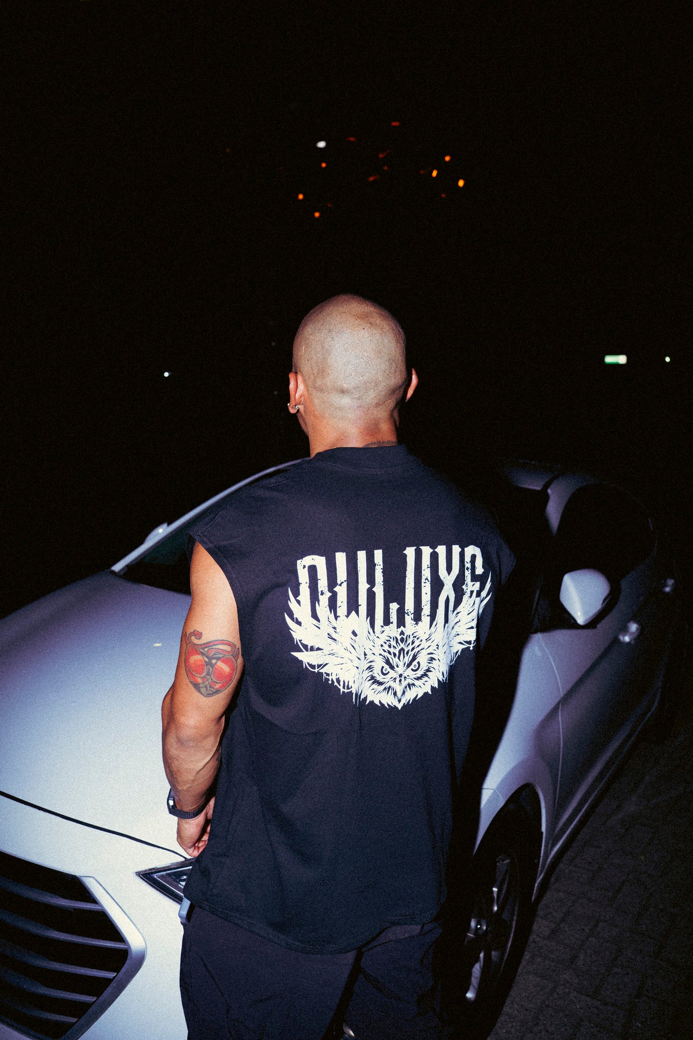 Camiseta sin mangas oversize negra con búho en la espalda, foto de calle de noche